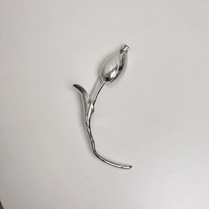 Detailed view of silver tulip bud brooch with elegant polished metal finish on grey