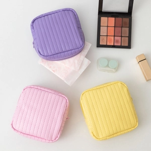Three macaron candy colors quilted leather cosmetic pouches with top zippers shown with makeup
