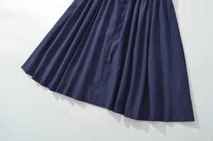 Detail of deep blue pleated dress showing vertical fabric texture and stitching