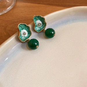 Detail of green enamel lotus leaf earrings with teardrop bead on ceramic tray