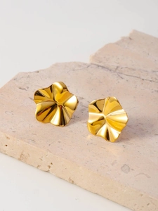 Macro shot of gold floral petal stud earrings on a textured stone display surface