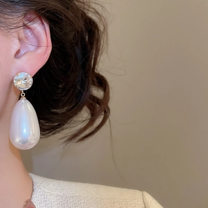 Detail of elegant silver needle drop pearl earrings with sparkling crystal accents