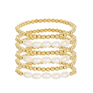 Set di 7 braccialetti impilabili con perle dorate e perle bianche su sfondo bianco puro