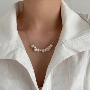 Close-up of elegant gold chain with white baroque pearls worn on a female neck