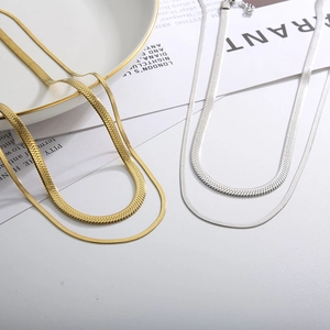 Double layered 18k gold and silver herringbone snake chain necklaces on a white background