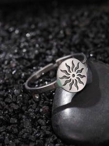 Detail of silver sun totem ring on black pebble with adjustable open band design