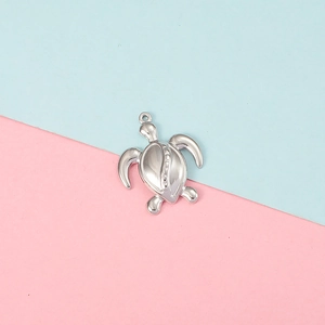 Polished silver sea turtle pendant accessory with top ring on colorful background