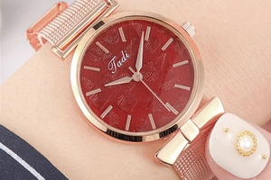 Gros plan sur une montre femme tendance avec cadran rouge à motifs et bracelet en maille