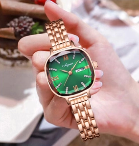 Gros plan sur une montre carrée or rose avec cadran vert et dateur sur un poignet