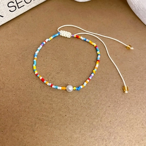 Detail of colorful seed bead bracelet with white pearl and adjustable cord