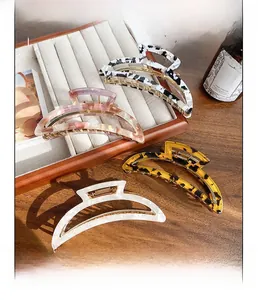 Detailed set of four tortoiseshell and marble acetate hair claws on a wooden tray
