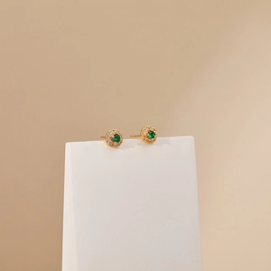Detail view of 18K gold-plated emerald stud earrings with halo of white zircon stones