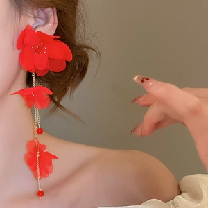 Close-up of long red fabric flower tassel earrings with gold beads on elegant model