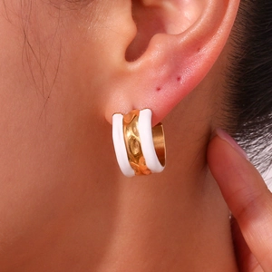 Detail of chunky C-shape hoop earring with golden water ripples and white enamel finish