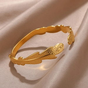 Detailed close-up of golden leaf-shaped open bangle with intricate dotted texture