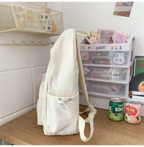 Detail view of cream white backpack side pocket with adjustable elastic drawstring cord