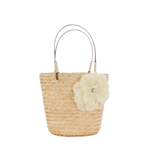 Borsa da spiaggia in paglia beige con un grande fiore decorativo in rete bianca su sfondo bianco