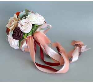 Detailed view of artificial bridal bouquet with champagne roses and flowing silk ribbons
