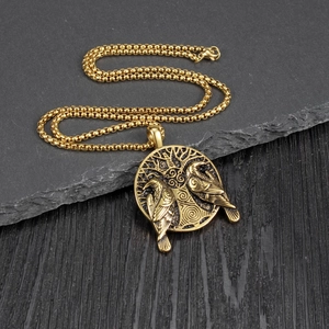 Vintage Viking crow pendant necklace in gold finish with Tree of Life on a slate background