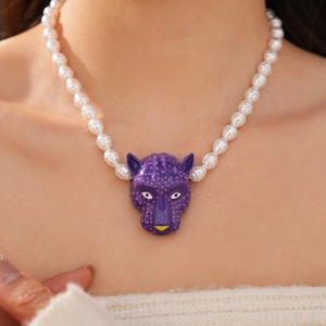 Détail d'un pendentif tête de léopard violet sur un collier de perles blanches
