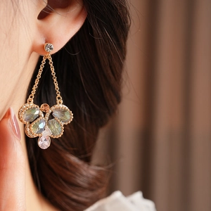 Close-up of vintage long drop earring with olive green and pink crystals on model