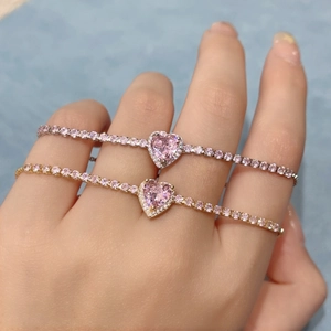 Gold and silver heart tennis bracelets with pink gemstones on a model's wrist