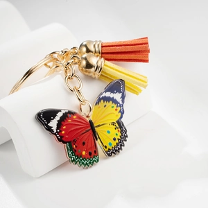 Colorful butterfly keychain with vibrant tassels and gold ring on white display stand