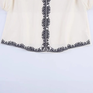 Women's cream-white blouse featuring contrast black floral embroidery and front buttons