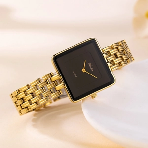 Detail of a square gold quartz watch with black dial on a minimalist white plate