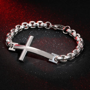 Detailed close-up of a silver stainless steel cross pendant on a bold curb chain bracelet