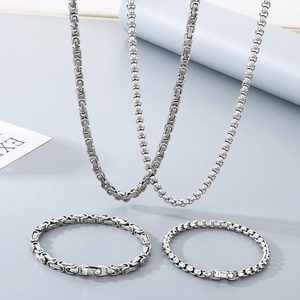 Disposition détaillée de colliers et bracelets en chaîne tressée argentée sous éclairage studio