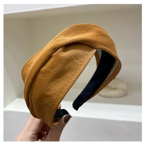 Detailed macro of mustard yellow wide faux leather headband with pleated texture design