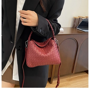 Detail of hand-woven dark red leather handbag featuring texture and silver hardware