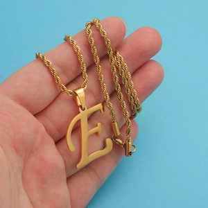 Elegant gold letter E pendant on a twisted rope chain necklace held in hand