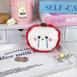 Plush apple coin purse with sad face shown with coins for size comparison in macro view
