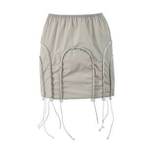 Détail de la mini-jupe grise avec taille élastique, cordon et pendentifs en perles