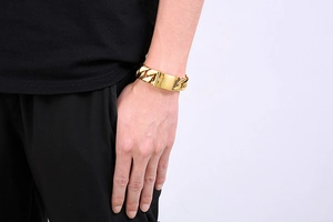 Close-up of a wide 20mm gold Cuban link chain bracelet with rectangular buckle on wrist