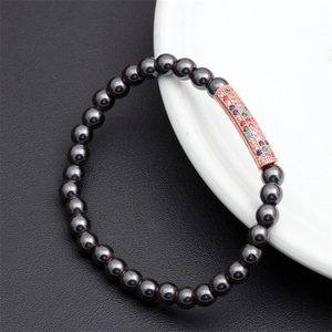 Close-up of black matte beaded bracelet featuring a rose gold tube with multi-color zircons