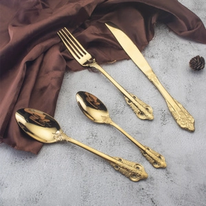 Details von goldenem Edelstahlbesteck mit geprägten Mustern auf Seidenstoff