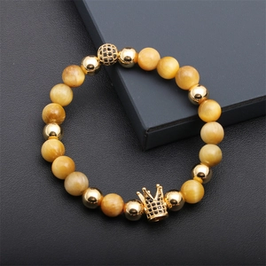 Macro view of luxury beaded bracelet with yellow tiger eye stones and gold crown charm