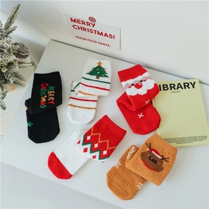 Gros plan de chaussettes de Noël en molleton corail avec motifs de rennes et du Père Noël