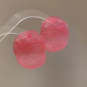 Macro shot of pink resin earrings with brushed texture and irregular oval shape