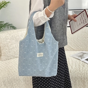 Détail du sac fourre-tout en velours côtelé bleu clair avec motifs de nœuds blancs