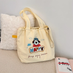 Detail of cute puppy embroidery and drawstring closure on soft yellow canvas tote bag