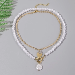 Detailed view of layered baroque pearls and golden metal chains on a minimalist background