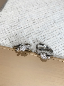 Macro shot of silver knotted rings with pavé cubic zirconia on textured fabric and leather