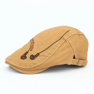 Detail of tan cotton flat cap featuring side embroidery and adjustable metal buckle