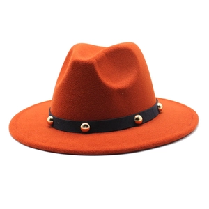 Detailed shot of orange wool fedora featuring black band with gold rivet studs