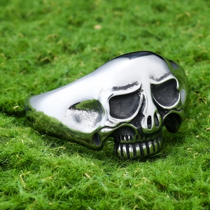 Macro shot of silver stainless steel skull ring with vintage gothic details on moss