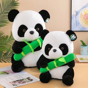 Adorable panda plush toys holding green bamboo stalks on a warm desk background.